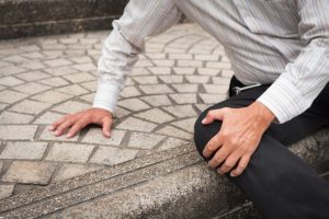 man on ground holding knee in pain