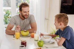 cheerful father and son eating breakfast